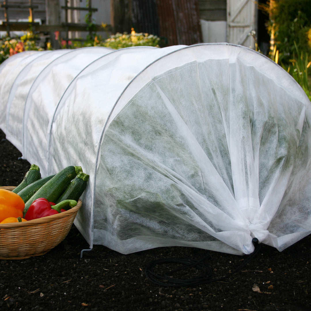 easy fleece garden tunnel in a garden with a basket of vegetables including courgettes and peppers next to it 