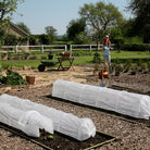 two easy fleece garden tunnels in a sunny garden with a standing female and a toddle on her shoulders