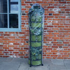 Vigoroot Self Watering Tower Garden with tomato plants in them next to a brick wall. The tower covered with a plastic cover