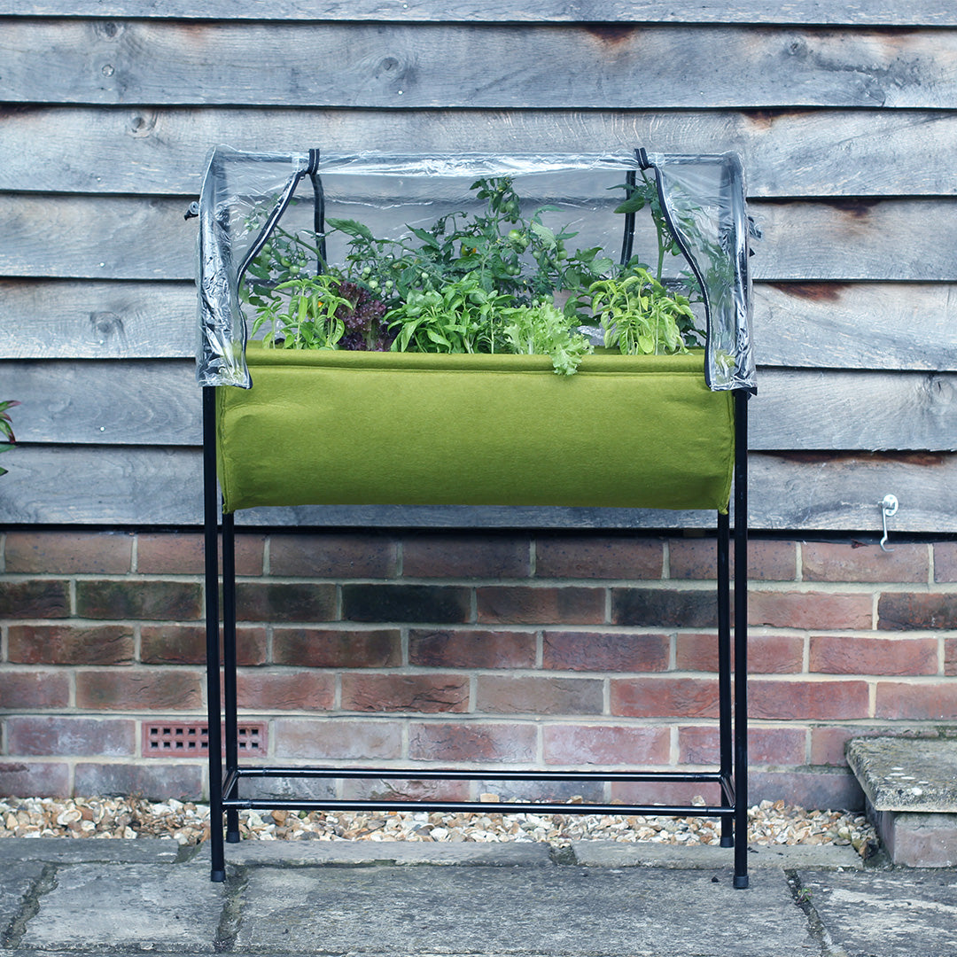 Vigoroot fabric table planter with many different types of plants inside it next to a wooden wall